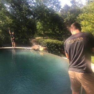 A Liquidus Pools pro skims a pool surface during weekly maintenance