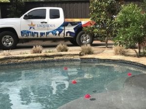 A Liquidus Pool Services truck parked beside a client's pool that needs weekly maintenance