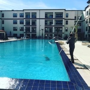 a man cleaning an apartment pool