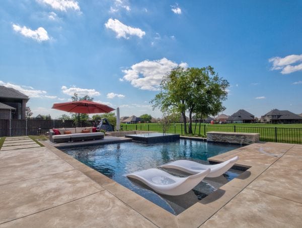 a backyard with fire pit seating, pool and spa