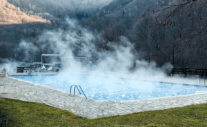 A heated pool with steam coming off the water. 