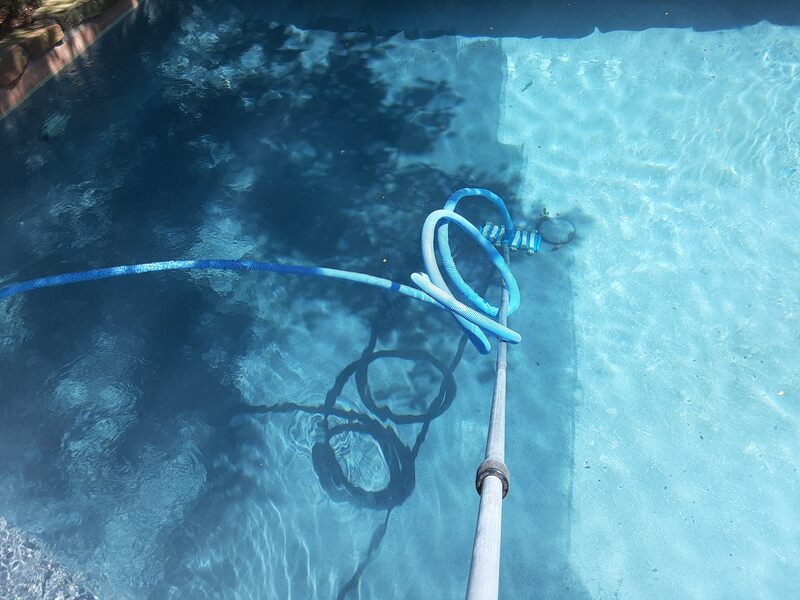 sweeping and vacuuming the bottom of a pool